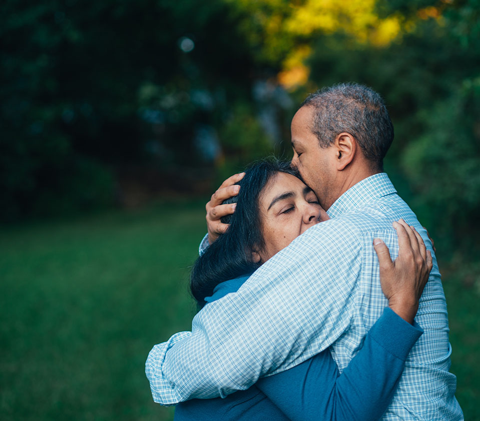 Older couple hugging outside both with eyes closed