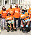 Group of people, including two in wheelchairs, wearing orange