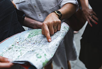 Man's hand pointing to location on a paper map that a second person is holding