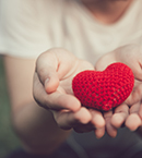 Hands holding a red wool heart