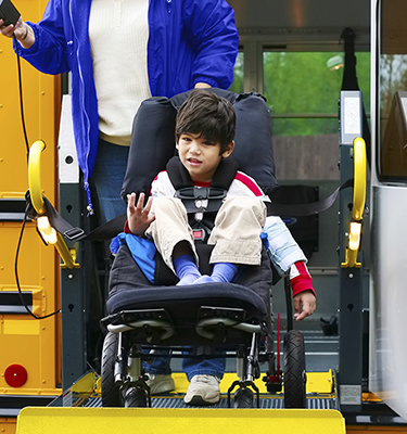 Young boy on a school bus wheelchair lift