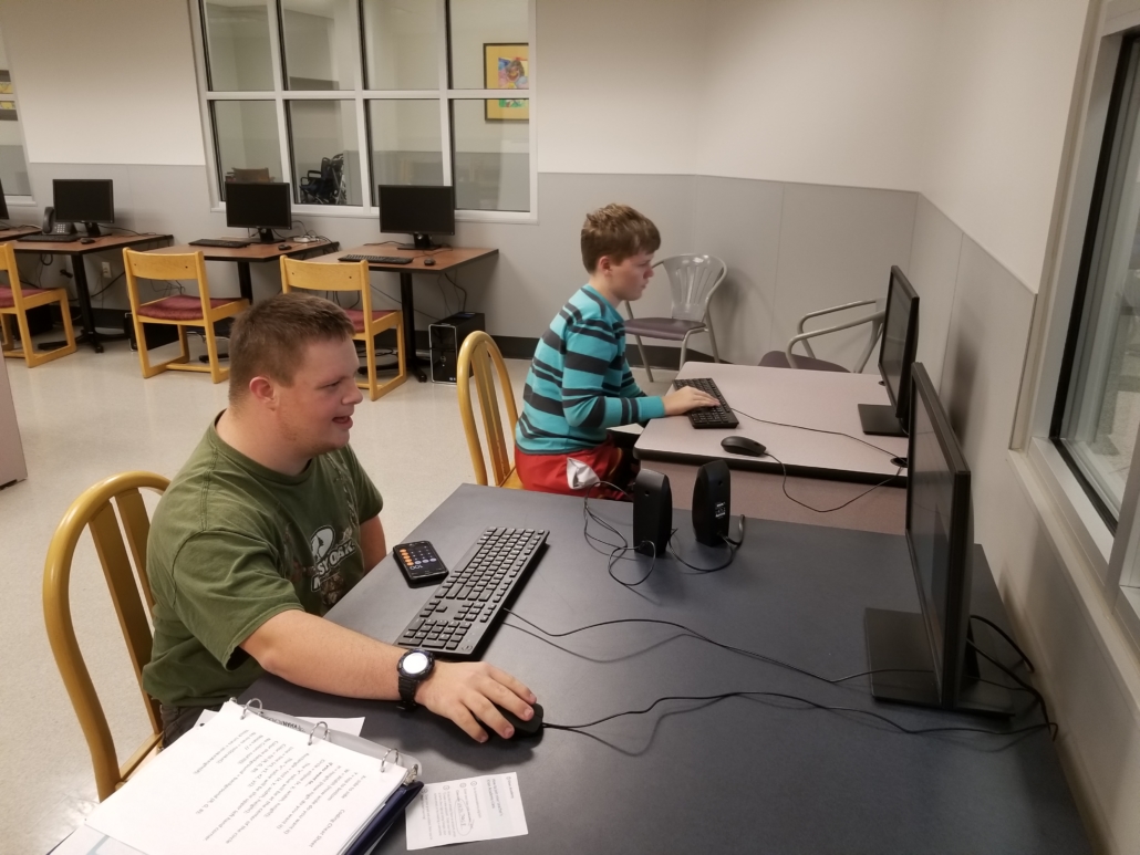 Tech_coaching Two students sit in a computer lab in school, intently focused on their computer work.