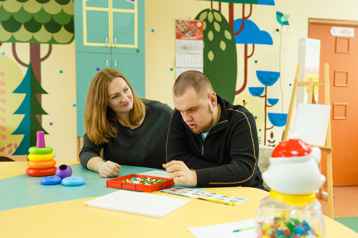 Person with Autism sitting with a teacher at a table in a one-on-one classroom setting