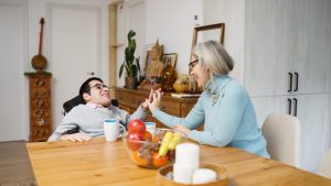 Disabled individual in a wheelchair interacting with a woman at a dining table
