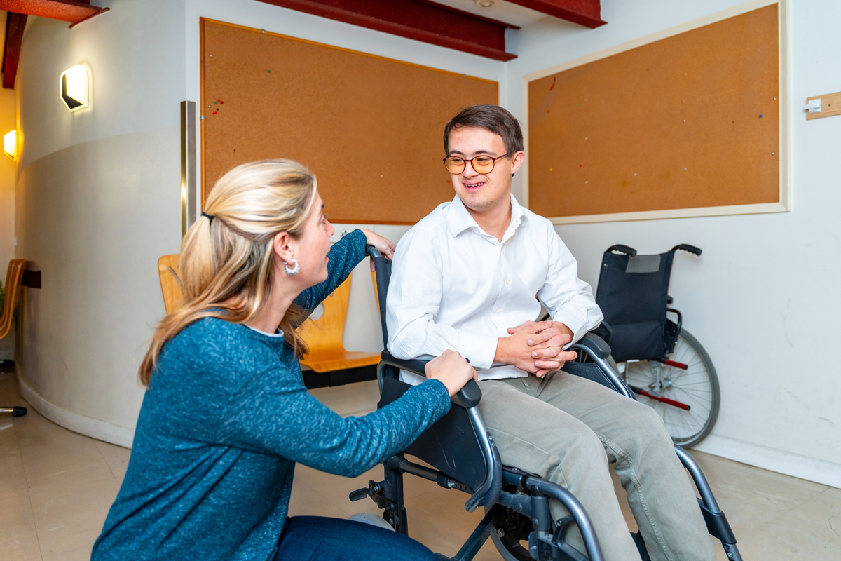 Man with down syndrome sitting in a wheelchair talking to a woman