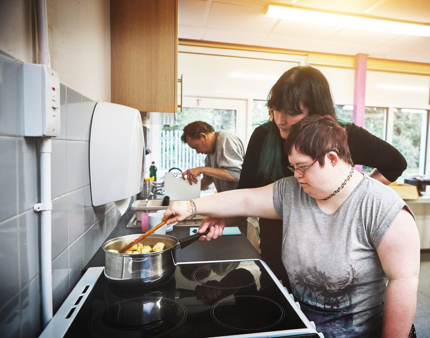 Person assisting a woman with down syndrome with cooking